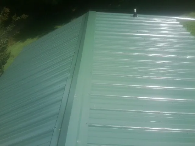 New green metal panels meeting at the ridge of a roof — Flat Roof Repair work by our crew in Chimayo