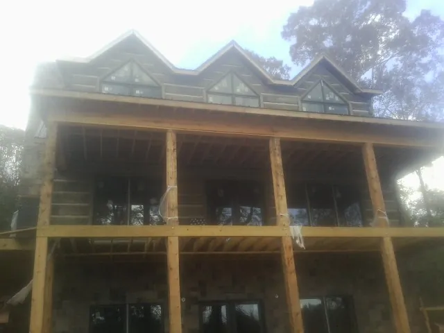 Dormers and porch framing on a large log home under construction — Roof Coating work by our crew in Chimayo
