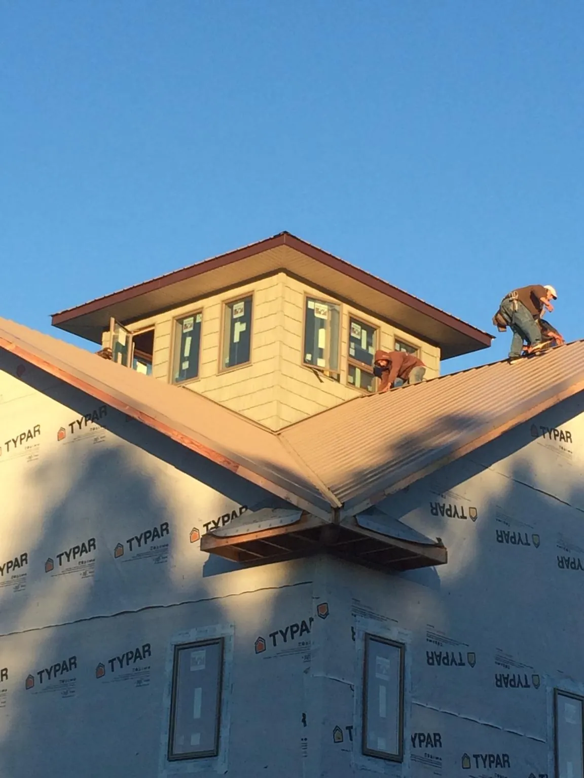 Roofers working around a rooftop cupola on a new metal roof at sunset — Roof Waterproofing in Chimayo by Roofing Brothers